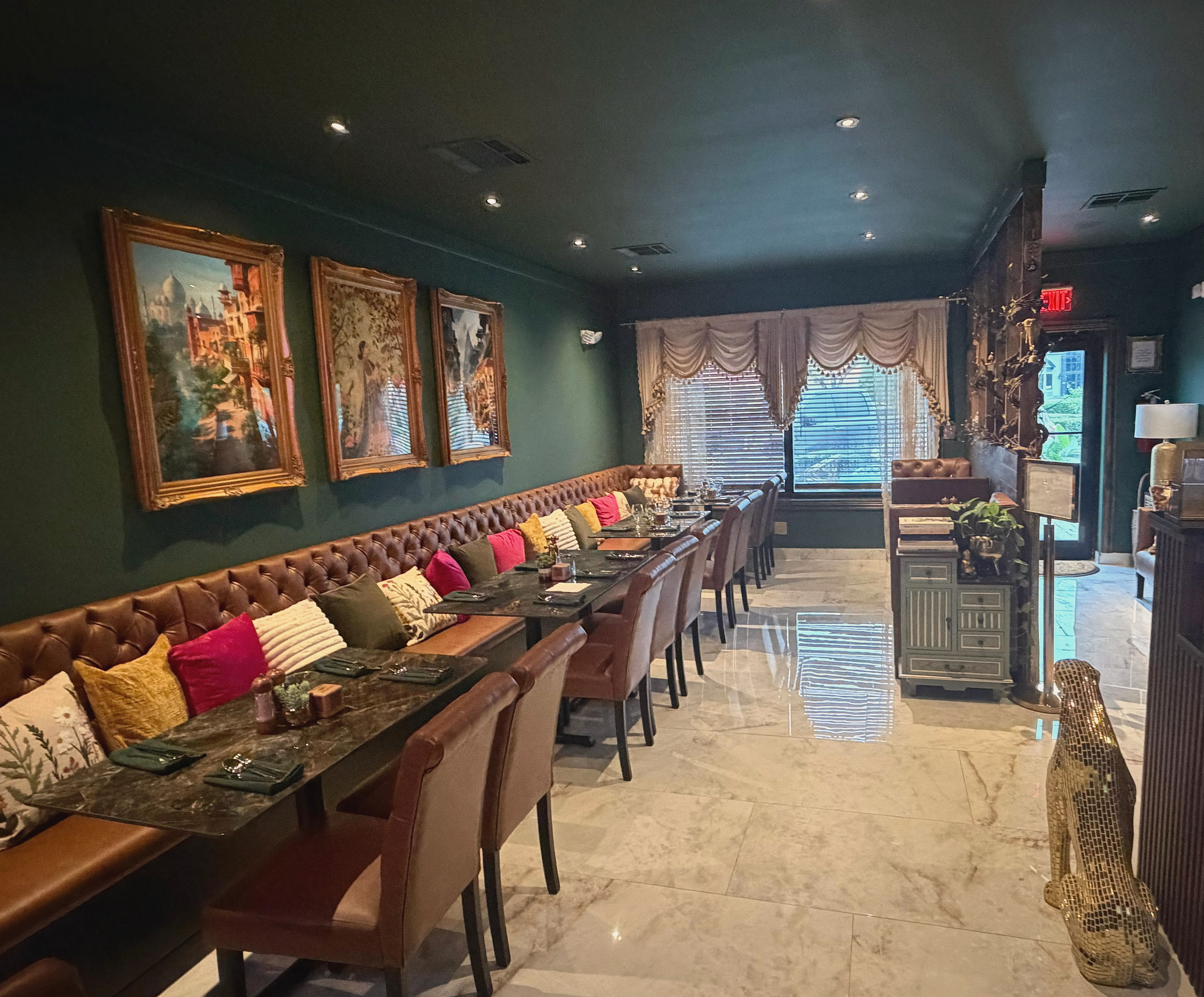The khana kh'zana dining room: emerald walls, leather banquettes and gold-framed paintings